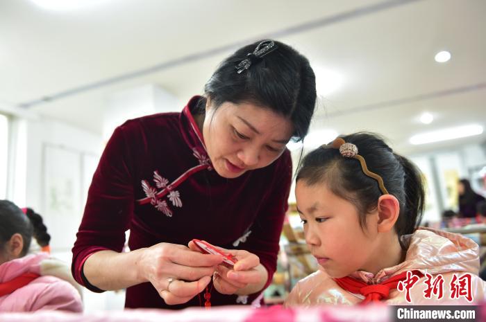 江西省級(jí)非遺豫章繡傳承人手把手指導(dǎo)小學(xué)生繡制2022年北京冬奧會(huì)吉祥物“冰墩墩”形象。　喻云亮 攝