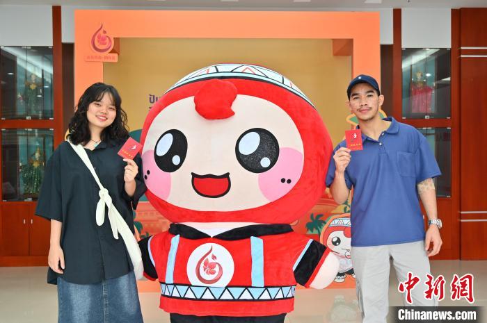圖為泰國(guó)留學(xué)生手持獻(xiàn)血證與人偶合影?！∮峋?攝