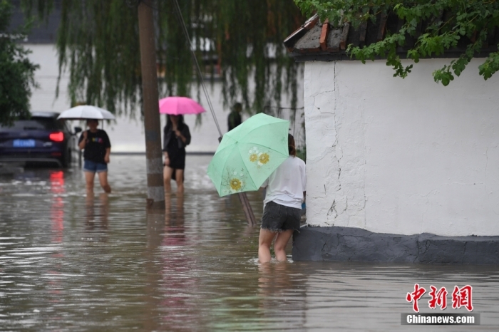 7月31日，市民行走在雨中的北京房山區(qū)瓦窯頭村。北京市氣象臺當(dāng)日10時(shí)發(fā)布分區(qū)域暴雨紅色預(yù)警信號。北京市水文總站發(fā)布洪水紅色預(yù)警，預(yù)計(jì)當(dāng)日12時(shí)至14時(shí)，房山區(qū)大石河流域?qū)⒊霈F(xiàn)紅色預(yù)警標(biāo)準(zhǔn)洪水。<a target='_blank' href='/'><p  align=