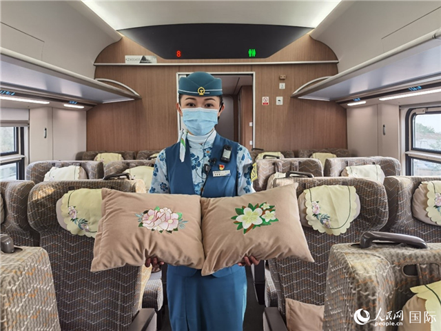 趙瑩靜展示中老鐵路國際旅客列車?yán)飵в兄袊档せê屠蠐胝及突ù汤C圖案的靠墊。人民網(wǎng)記者 杜明明攝
