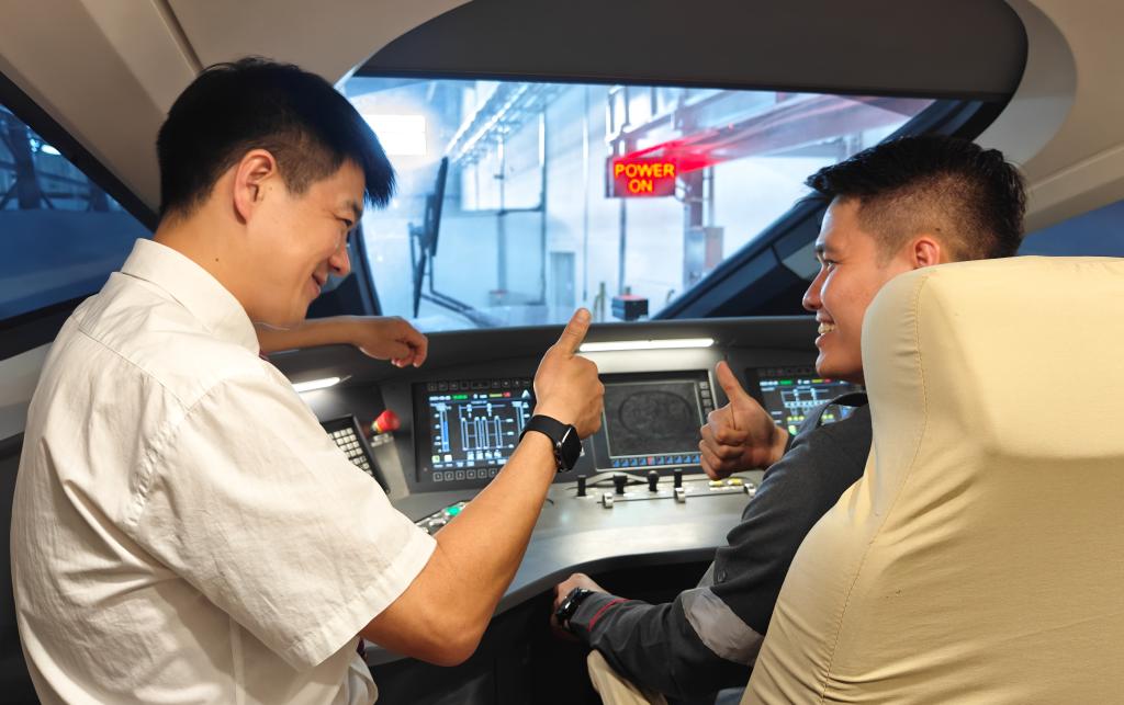 8月25日，在印度尼西亞萬隆的雅萬高鐵德卡魯爾動車所內(nèi)，中國師傅穆振（左）在向印尼火車司機(jī)塞蒂亞萬講解動車組出庫前的上電作業(yè)。
