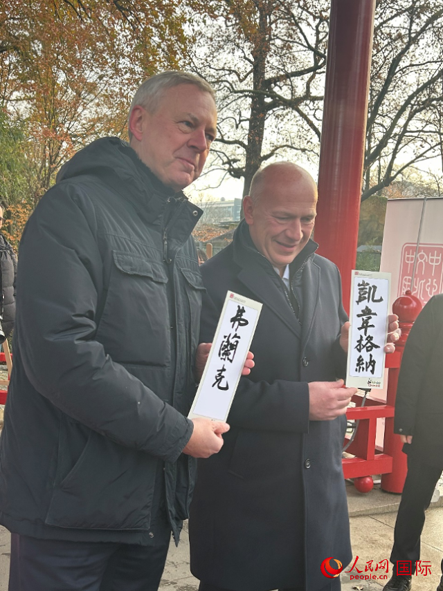 柏林市長韋格納（右）、動物園監(jiān)事會主席布魯克曼（左）手持中國文化中心工作人員現(xiàn)場手書的中文名字。人民網(wǎng)記者 徐馨攝