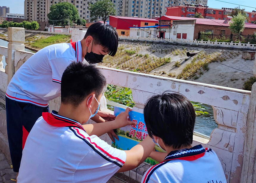 徐水小學(xué)學(xué)雷鋒志愿者在瀑河河邊張貼防溺水警示標(biāo)語(yǔ)。 徐水區(qū)委宣傳部供圖