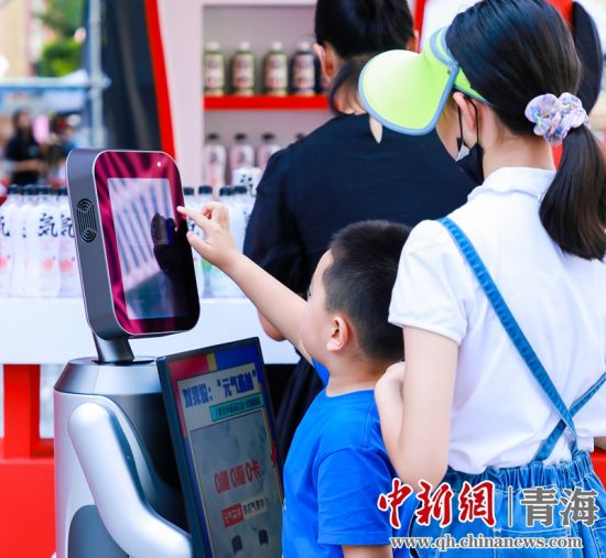 圖為一名小朋友正在和機(jī)器人“志愿者”進(jìn)行互動(dòng)。 沐聞 攝