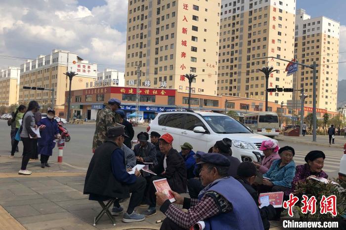 圖為會澤縣城易地扶貧搬遷安置點(diǎn)內(nèi)，老人們聚在廣場上聊天，身后是他們的新家。　繆超 攝
