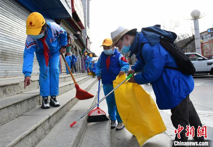 圖為拉薩市小學(xué)生打掃街道?！∝暩聛?lái)松 攝