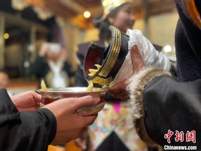 圖為主人在碗中斟滿青稞酒?！∪轿木?攝