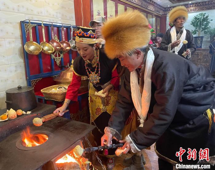 圖為人們在火上烤節(jié)日美食“結(jié)達”?！∪轿木?攝