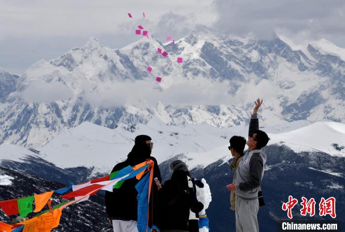 圖為5月14日，游客在西藏林芝色季拉山觀景臺(tái)拋灑“隆達(dá)”(風(fēng)馬旗，藏族民眾的一種祈福方式)?！±盍?攝